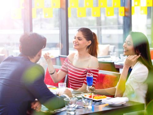 a group of people sitting around a table in a restaurant at Novotel Kolkata Hotel and Residences in Kolkata