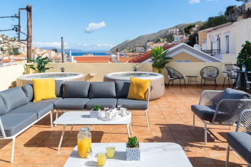 een patio met banken en tafels op een dak bij Maravelia's Rooms in Symi