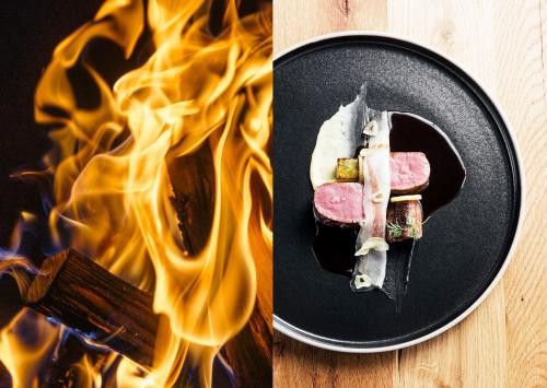 a plate of food with a piece of meat on fire at Maiensässhotel Guarda Val in Lenzerheide