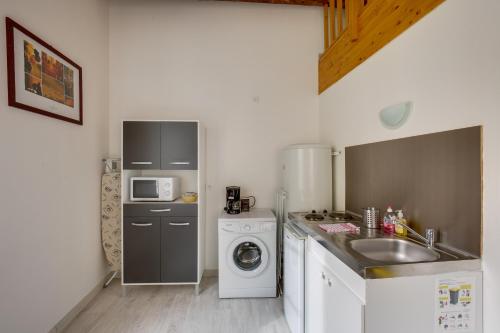 a kitchen with a sink and a washing machine at Logis Andraud Studios in Saint-Émilion