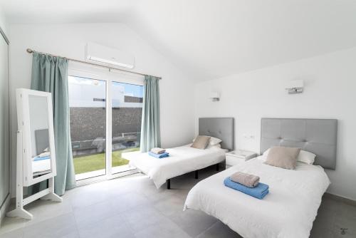 a bedroom with two beds and a large window at Villa Rossa - Villas Now - LH215 By Villas Now Ltd in Playa Blanca