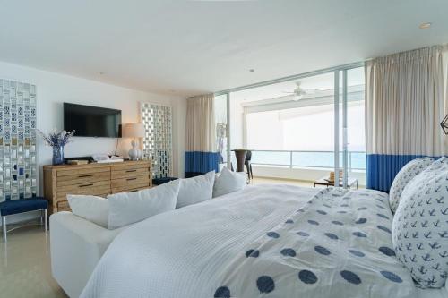 a bedroom with a large white bed and a large window at Luxury penthouse portobello in Santo Domingo