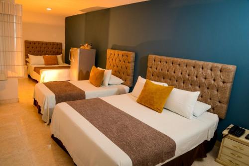 a hotel room with two beds with yellow pillows at Hotel Prado 34 West in Bucaramanga