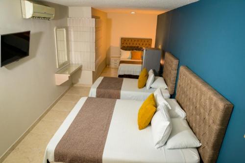 a bedroom with two beds and a blue wall at Hotel Prado 34 West in Bucaramanga