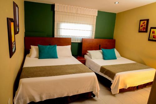 two beds in a room with green walls at Hotel Prado 34 West in Bucaramanga