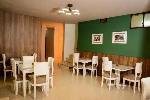 a restaurant with white tables and chairs and a green wall at Hotel Prado 34 West in Bucaramanga