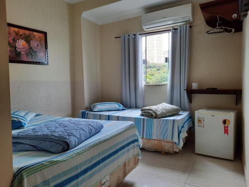 two beds in a room with a window at Pousada Mãe Ternura Palace in Aparecida