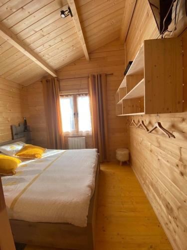 une chambre avec un lit dans une cabane en bois dans l'établissement Les Chalets Du Marais, à Saint-Pierre-Aigle