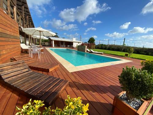 una piscina en una terraza de madera con bancos y sombrilla en Hotel MANDALA BEACH CHIHUAHUA Naturista Nudista Opcional -Exclusivo Adultos-, en Punta del Este