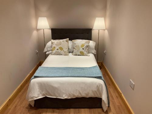 Un dormitorio con una cama grande con dos lámparas. en Dove Cottage (Annex), en Workington