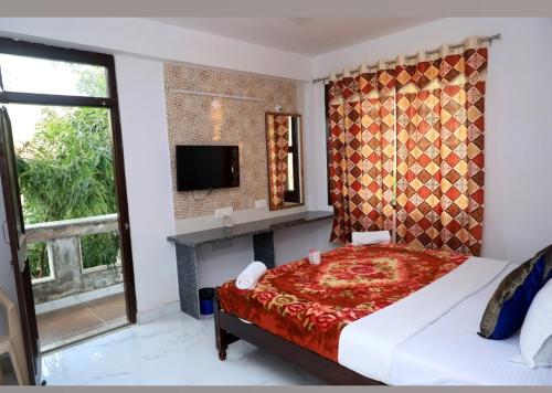 Un dormitorio con una cama y un televisor y una ventana. en Brahma Paradise , A heritage haveli, en Pushkar