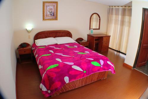 a bedroom with a bed with a pink comforter at Hotel Santa Isabel 2 in Ipiales