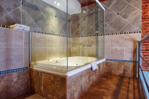 a bathroom with a tub and a glass shower at La Fresque Hotel in Buenos Aires
