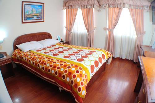 a bedroom with a bed with an orange and white blanket at Hotel Santa Isabel 2 in Ipiales