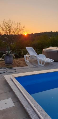 a lounge chair next to a swimming pool with the sunset at Kuća za odmor Mladen i Martina in Slavonski Brod
