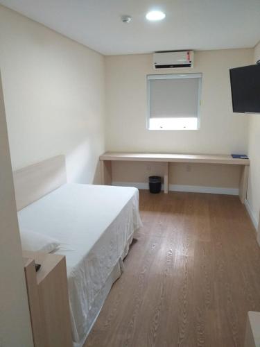 a bedroom with a bed and a desk and a window at Hotel Hetropolis in São Bernardo do Campo