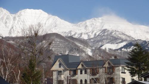 a house in front of a snow covered mountain at Hotel El Mayo in Hakuba