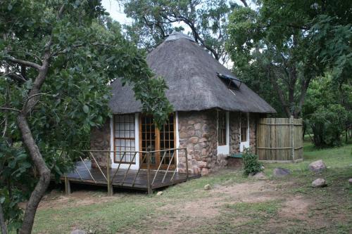 una pequeña casa de piedra con techo de hierba en Griffons Bush Camp, en Thabazimbi