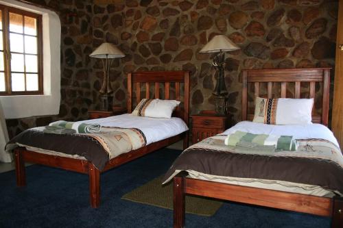 a bedroom with two beds and a stone wall at Griffons Bush Camp in Thabazimbi