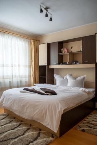 a bedroom with a large bed with white sheets and a window at APARTAMENT ALESSI BUȘTENI in Buşteni