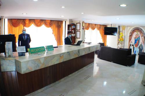 a lobby with a bar with two men in suits at Hotel Santa Isabel 2 in Ipiales