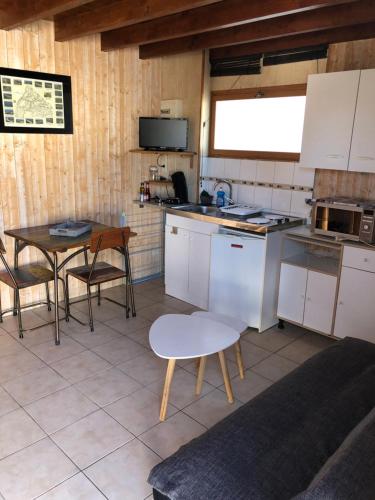 une cuisine avec des armoires blanches et une table et des chaises dans l'établissement Studio Duplex, à La Teste-de-Buch