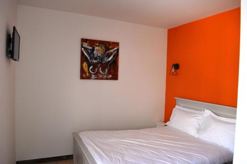 Ce lit se trouve dans un dortoir doté d'un mur orange. dans l'établissement Résidence L'art Doise, à Rochefort