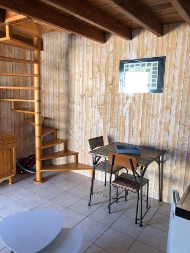 - une table et des chaises dans une chambre dotée d'un mur en bois dans l'établissement Studio Duplex, à La Teste-de-Buch