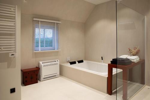 a bathroom with a bath tub and a window at Wabi Sabi B&B in Peer