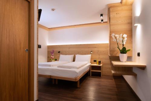a bedroom with a bed and a vase of flowers at HOTEL B&B MARILENA in Arabba
