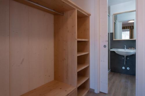 a bathroom with a sink and a wooden closet at HOTEL B&B MARILENA in Arabba