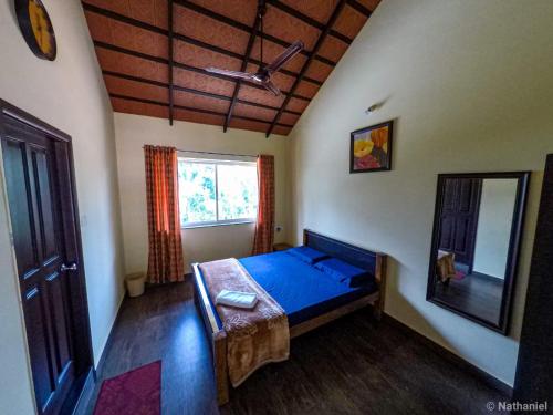 ein Schlafzimmer mit einem blauen Bett und einem Spiegel in der Unterkunft Foothills Homestay in Chikmagalur