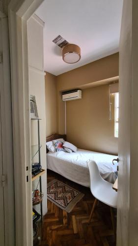 a small bedroom with a bed and a white chair at Habitacion Shabby Chic- next Consulado USA-Aeroparque Airport in Buenos Aires