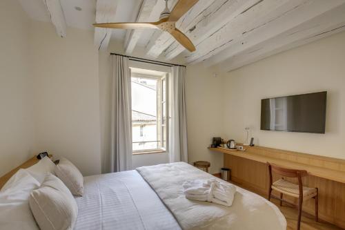 a bedroom with a bed with a ceiling fan and a television at Badon Boutique Hotel in Saint-Émilion