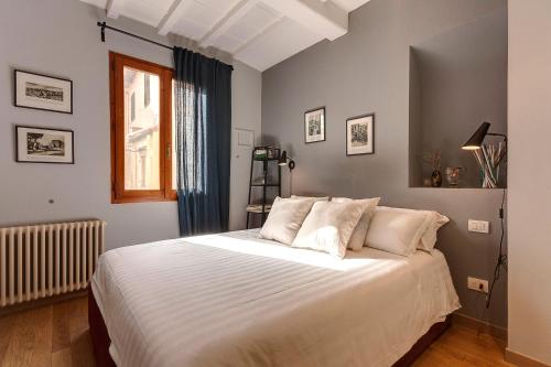 Schlafzimmer mit einem Bett mit weißer Bettwäsche und einem Fenster in der Unterkunft Mamo Florence - San Marco Apartment in Florenz