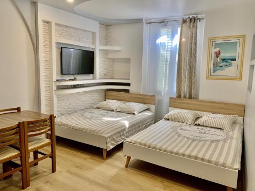 Cette chambre comprend 2 lits, une table et une télévision. dans l'établissement Excellent Studio au cœur historique de Fréjus, à Fréjus