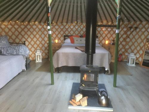 a room with a stove in a yurt with a bed at Penbedw Uchaf Estate - Rural retreats, tennis in Mold