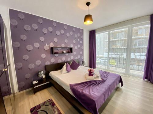a bedroom with a bed and a purple wall at Apartament Ella T8 in Mamaia Sat/Năvodari