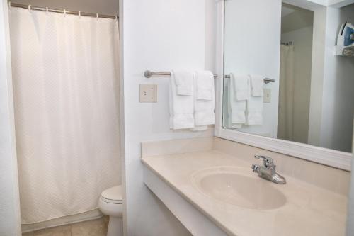 a bathroom with a sink and a toilet and a mirror at The Sea Ranch Resort in Kill Devil Hills