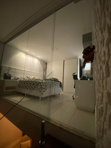 reflejo de una habitación con una cama en un espejo en Loft luxo duplex com dois colchões adicionais e sofá cama, en Salvador