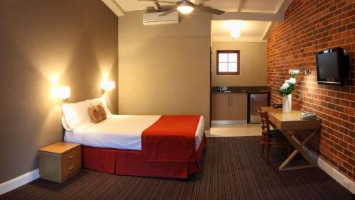 Habitación de hotel con cama y pared de ladrillo en Rose & Crown Hotel en Perth