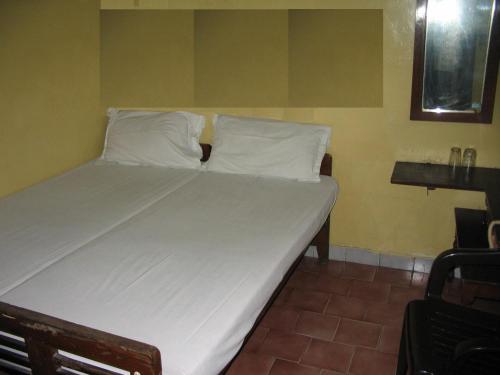 un letto con lenzuola e cuscini bianchi in una stanza di Vasantha Lodge Purasawalkam chennai a Chennai