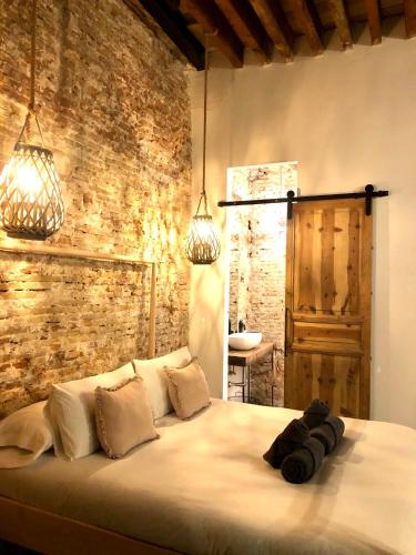a bedroom with a large white bed with a brick wall at Casa Poeta Pelayo in Cartagena