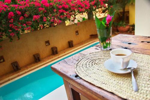 a table with a cup of coffee and a vase of flowers at Msafini Hotel in Lamu