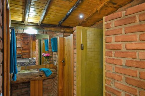 a bathroom with a sink and a brick wall at Pousada Lua de Minas in Visconde De Maua