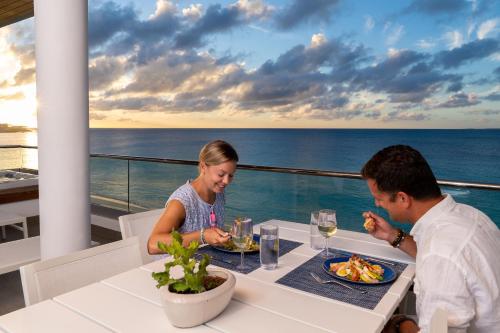 Un uomo e una donna seduti a un tavolo con un piatto di cibo di Tranquility Beach Anguilla Resort a Meads Bay
