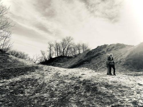a black and white photo of a couple standing on a hill at Potvis in Oostduinkerke