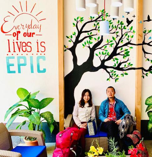 a man and woman sitting on a chair in front of a tree mural at Hotel y Arte Antigua by Amazing Guatemala Travel in Antigua Guatemala