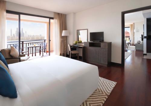 a hotel room with a white bed and a living room at Anantara The Palm Dubai Resort in Dubai