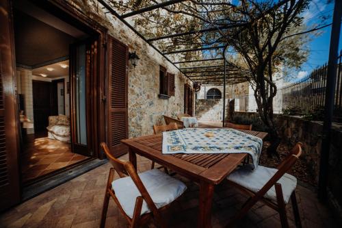 ein Holztisch und Stühle auf einer Terrasse in der Unterkunft Residenza Golfo Degli Ulivi in Caprioli